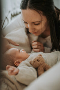 Newbornshooting einer Mutter die ihr Baby anlächelt